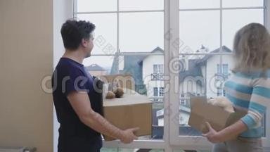 <strong>双手拿</strong>着盒子的成年男女在新房子的窗户里看着